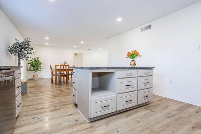 kitchen with white cabinets, light hardwood / wood-style flooring, and stainless steel dishwasher