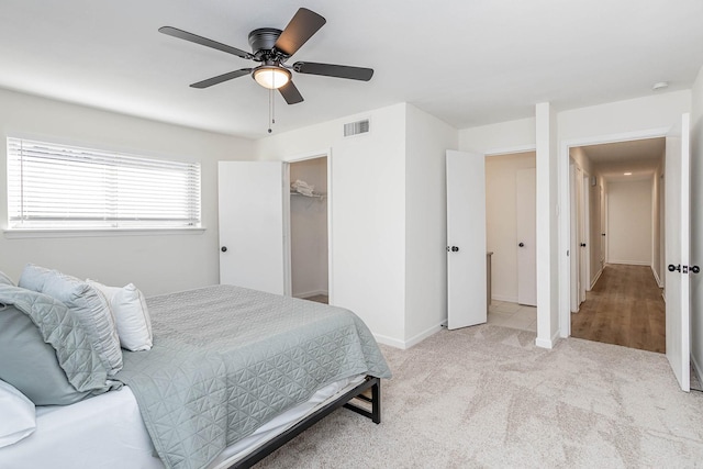 bedroom with a closet, light colored carpet, a spacious closet, and ceiling fan