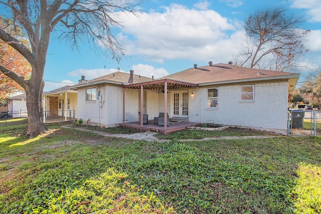 back of property with a yard, a wooden deck, and french doors