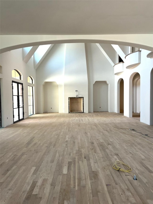 unfurnished living room featuring wood finished floors and high vaulted ceiling