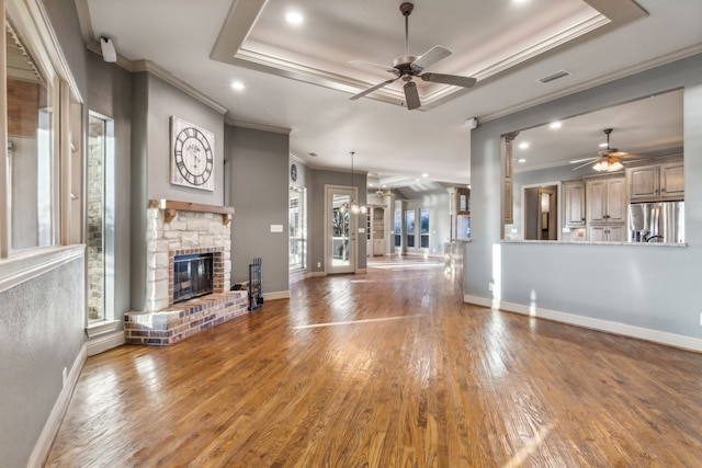 unfurnished living room featuring wood-type flooring, ornamental molding, a raised ceiling, and ceiling fan