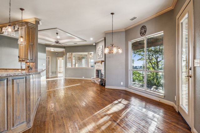 kitchen with decorative light fixtures, ceiling fan with notable chandelier, dark wood-type flooring, and a healthy amount of sunlight