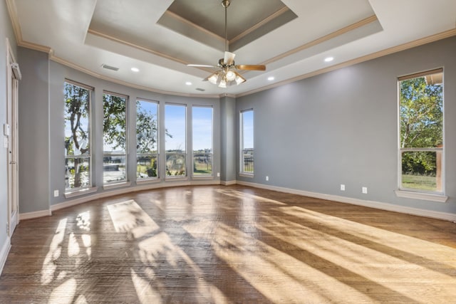 empty room with crown molding, ceiling fan, a tray ceiling, and hardwood / wood-style flooring