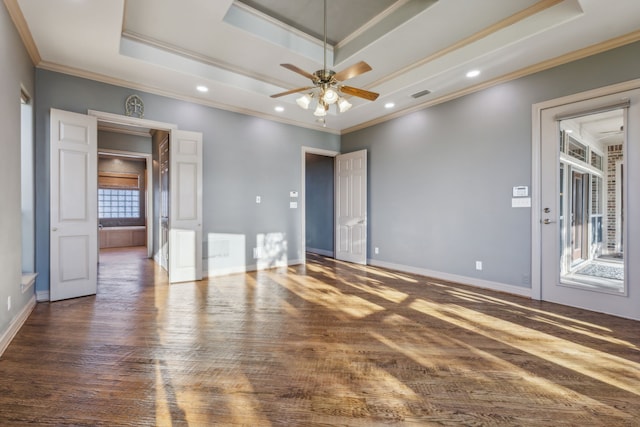 empty room with dark hardwood / wood-style floors, ceiling fan, ornamental molding, and a tray ceiling