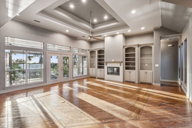 unfurnished living room with built in shelves, ceiling fan, french doors, crown molding, and wood-type flooring