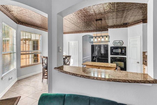 kitchen featuring black appliances, decorative light fixtures, kitchen peninsula, and light tile patterned floors