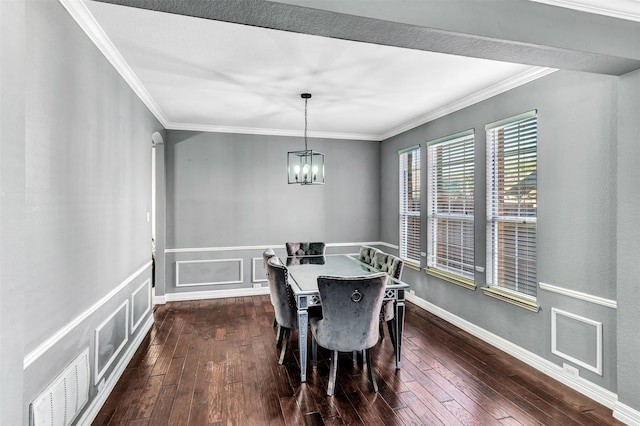 dining area with dark hardwood / wood-style floors, crown molding, and an inviting chandelier