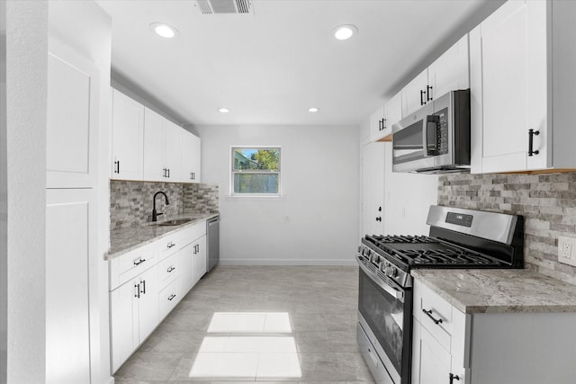 kitchen with white cabinetry, sink, stainless steel appliances, and light stone countertops