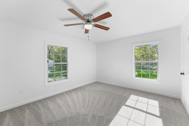 spare room featuring light carpet, a wealth of natural light, and ceiling fan