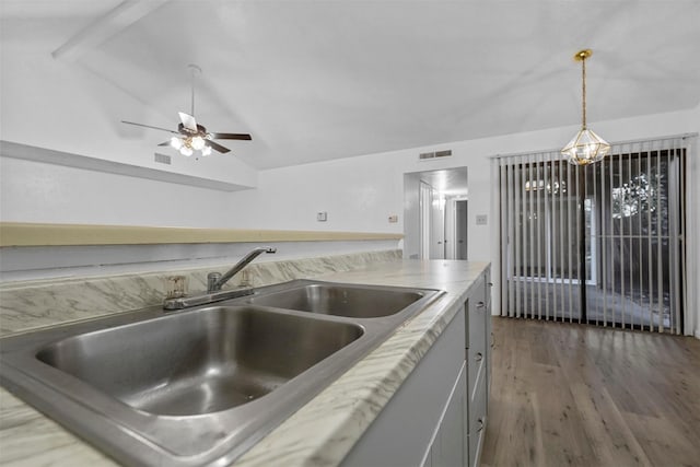 kitchen featuring lofted ceiling, sink, dark wood-type flooring, and decorative light fixtures