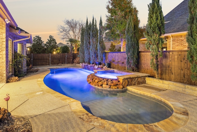 pool at dusk featuring an in ground hot tub