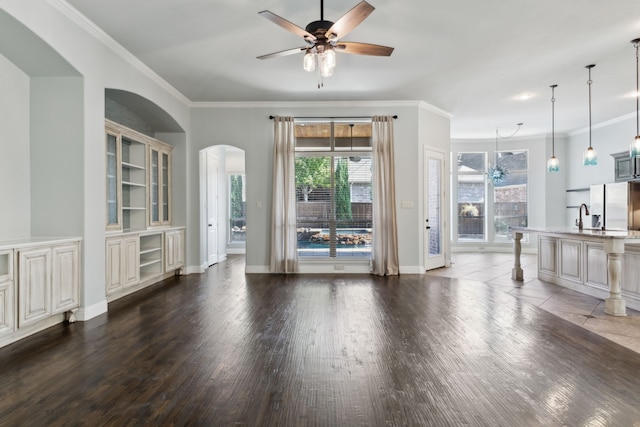 unfurnished living room with crown molding, dark hardwood / wood-style flooring, and ceiling fan