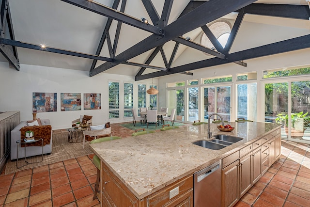 kitchen featuring dishwasher, an island with sink, a healthy amount of sunlight, and sink