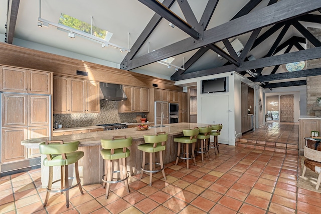 kitchen with a spacious island, wall chimney exhaust hood, a kitchen breakfast bar, and tasteful backsplash