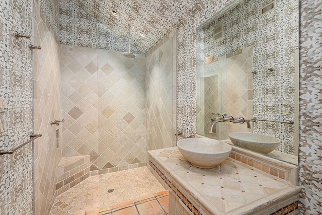 bathroom with tile patterned floors, tiled shower, and sink