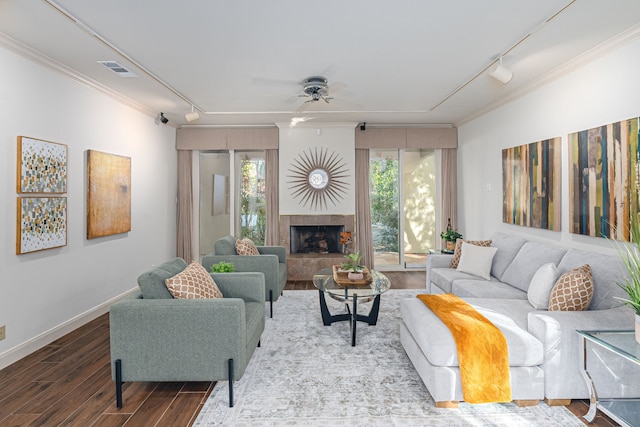 living room with a tile fireplace, ceiling fan, rail lighting, crown molding, and hardwood / wood-style flooring