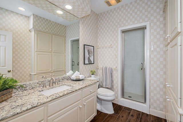 bathroom featuring hardwood / wood-style floors, vanity, toilet, and a shower with door