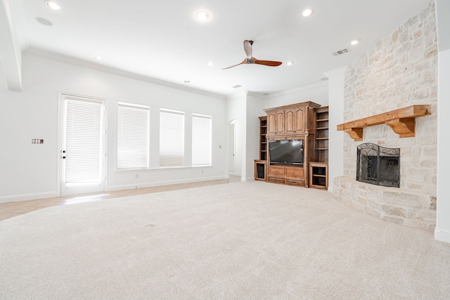 unfurnished living room featuring light carpet, a stone fireplace, ceiling fan, and ornamental molding