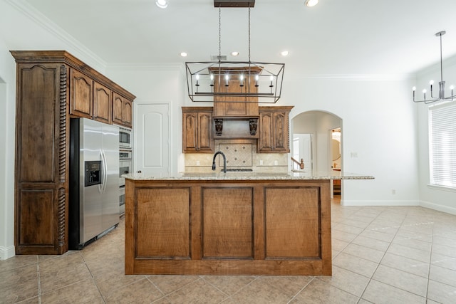 kitchen featuring light stone countertops, decorative backsplash, stainless steel appliances, a center island with sink, and hanging light fixtures