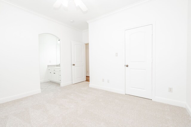 unfurnished bedroom with ceiling fan, light colored carpet, ornamental molding, and connected bathroom