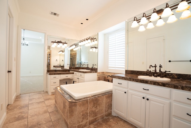 bathroom with tile patterned floors, vanity, crown molding, and tiled tub