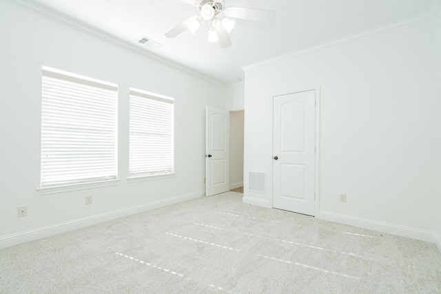 empty room featuring ceiling fan, crown molding, and light carpet