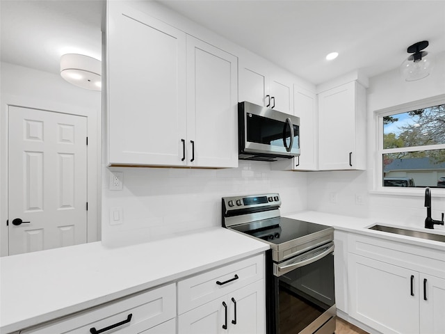 kitchen featuring white cabinetry, sink, backsplash, and appliances with stainless steel finishes