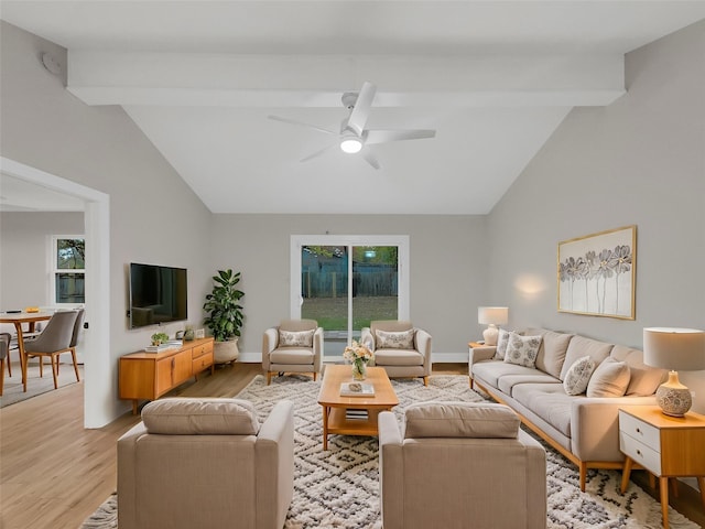 living room with ceiling fan, light hardwood / wood-style floors, and vaulted ceiling with beams