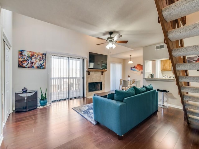 living room with ceiling fan, a fireplace, and dark wood-type flooring