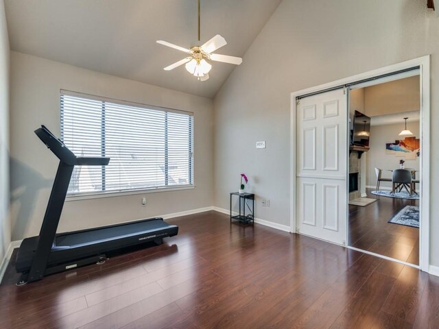 exercise area with ceiling fan, a barn door, dark hardwood / wood-style flooring, and high vaulted ceiling