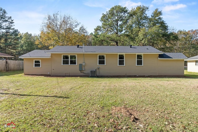 rear view of house featuring central air condition unit and a lawn