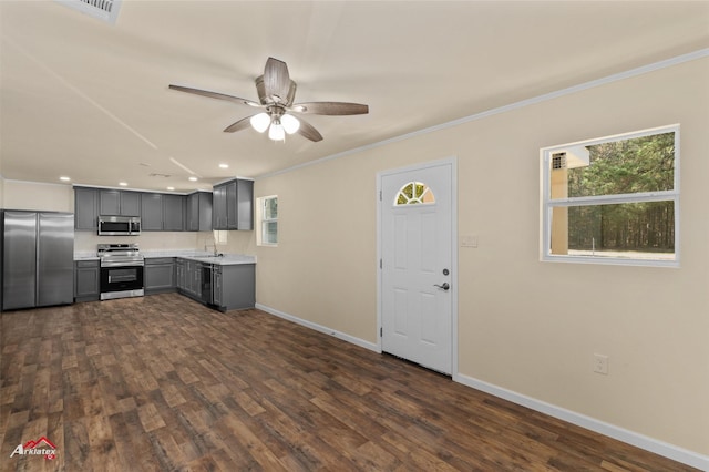 kitchen featuring ornamental molding, stainless steel appliances, dark wood-type flooring, and gray cabinetry