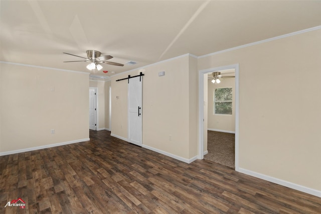 spare room with a barn door, crown molding, and dark wood-type flooring