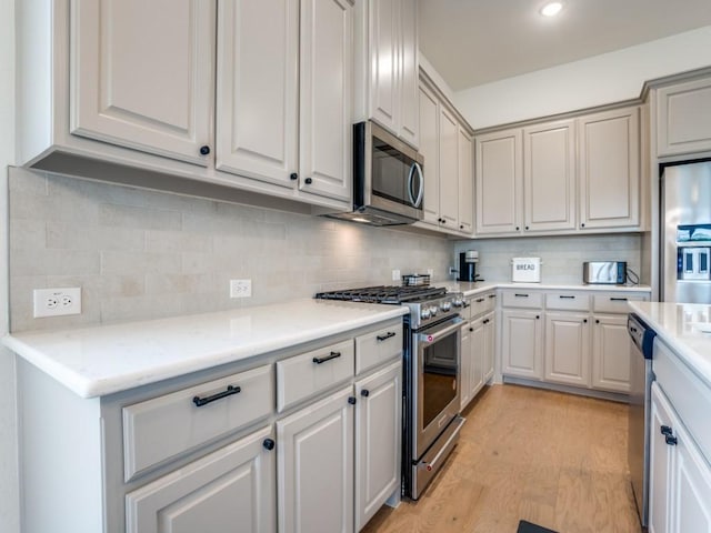 kitchen featuring decorative backsplash, light hardwood / wood-style flooring, and appliances with stainless steel finishes