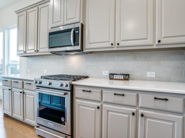 kitchen featuring light hardwood / wood-style floors, backsplash, and appliances with stainless steel finishes