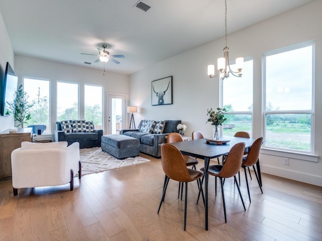 dining area featuring a wealth of natural light, hardwood / wood-style floors, and ceiling fan with notable chandelier