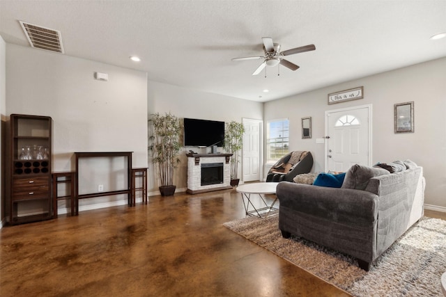 living room featuring a textured ceiling, ceiling fan, and a fireplace