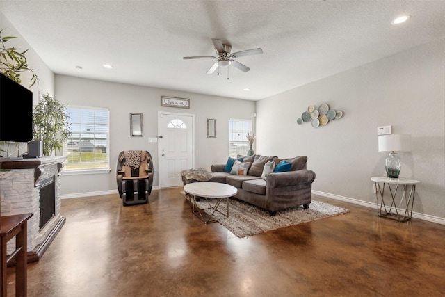 living room featuring ceiling fan, a fireplace, and a textured ceiling