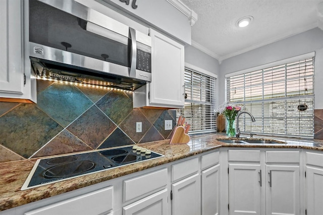 kitchen with tasteful backsplash, crown molding, sink, electric cooktop, and white cabinets