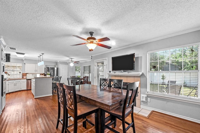 dining area featuring hardwood / wood-style floors, ceiling fan, ornamental molding, and a textured ceiling