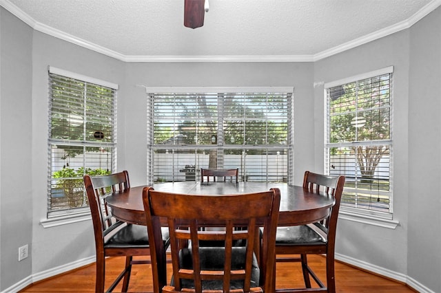 dining space featuring hardwood / wood-style flooring, ornamental molding, and a textured ceiling