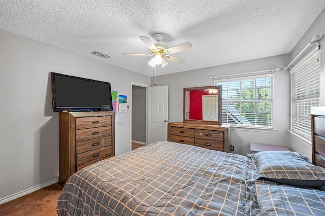 bedroom with ceiling fan, carpet floors, and a textured ceiling