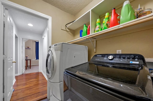 laundry room featuring hardwood / wood-style flooring, washer and clothes dryer, and a textured ceiling