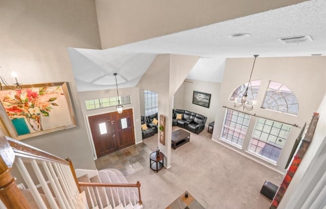 carpeted living room with a towering ceiling, a textured ceiling, and an inviting chandelier