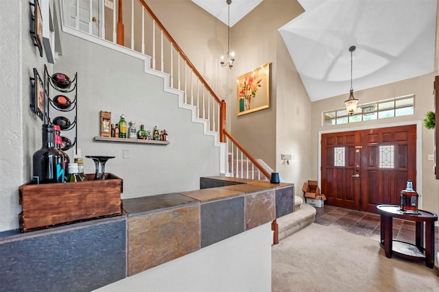 foyer featuring carpet floors, an inviting chandelier, and high vaulted ceiling