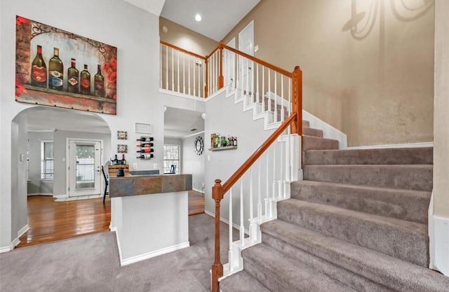 staircase featuring a towering ceiling and wood-type flooring