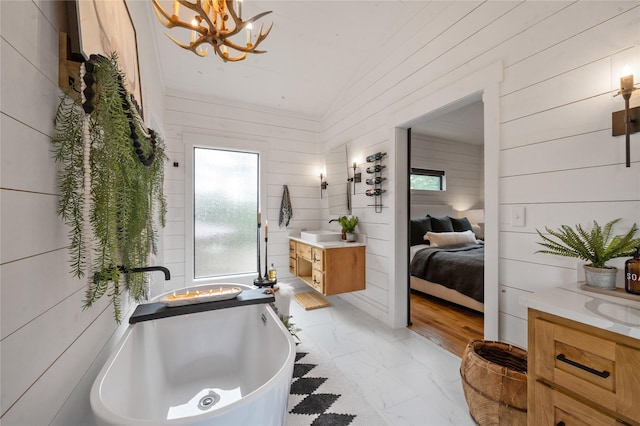 bathroom with a tub, wooden walls, vanity, and an inviting chandelier