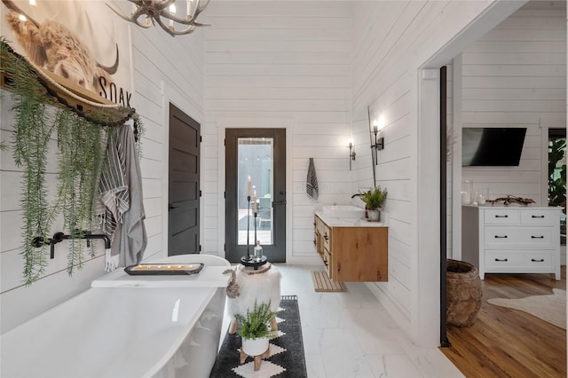 bathroom featuring vanity, high vaulted ceiling, a bathing tub, wooden walls, and wood-type flooring