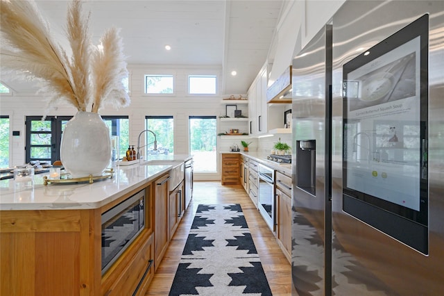 kitchen featuring a wealth of natural light, white cabinetry, stainless steel appliances, and a large island with sink