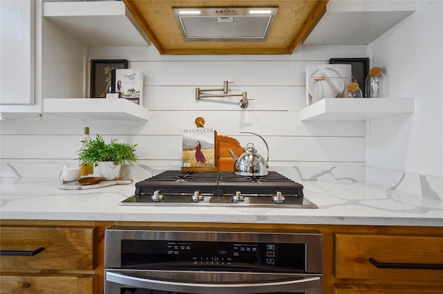 kitchen featuring tasteful backsplash, light stone counters, black gas stovetop, and stainless steel oven